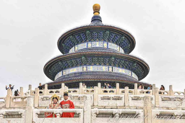 Una pareja vestida en traje tradicional sonríe para una foto en el Templo del Cielo.