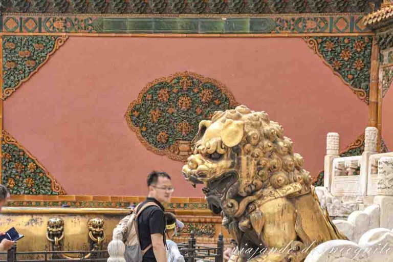 Un hombre pasa frente a unos de los leones dorados en la Puerta de la Pureza Celestial