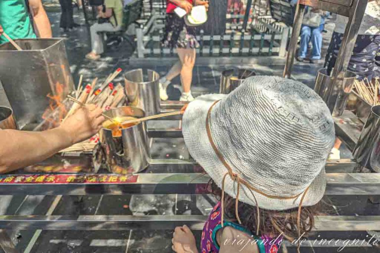 Una niña con sombrero blanco quema inciendo en el templo de los Lamas de Pekín.