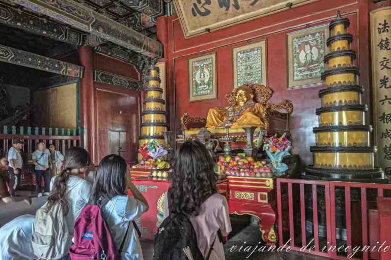 Varias personas rezan frente al Buda Maitreya de la Sala de la puerta de la Armonía.