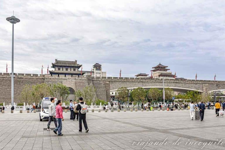 Varias personas caminan frente a la antigua muralla de Xian en el tramo que está frente a la estación central.